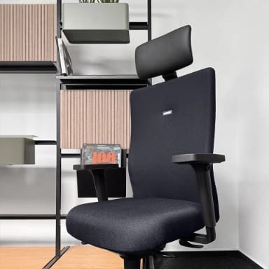 Seitenansicht des ergonomischen Bürostuhls agilis start-up in Schwarz mit verstellbarer und neigbarer Kopfstütze, im Hintergrund ein Bücherregal.