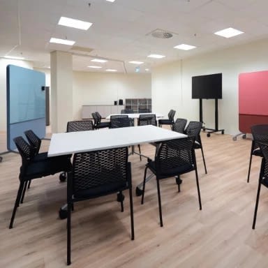 Meetingraum für Besprechungen mit Büroeinrichtung von lento, ausgestattet mit Bildschirm, Schreibtischen und stapelbaren Stühlen für flexible Meetings im Büro
