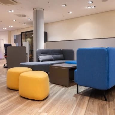 Großraumbüro mit Büroeinrichtung von lento, mit integrierter Ruhezone und Wartebereich, ausgestattet mit Sitzhockern und Sofa für flexible Nutzung im Arbeitsumfeld
