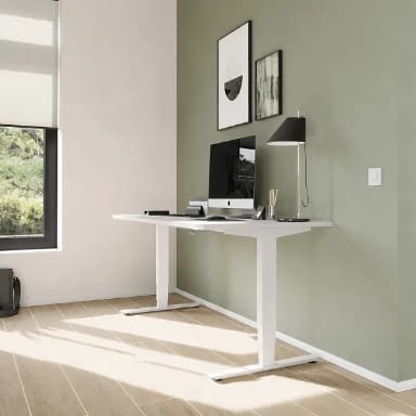 Höhenverstellbarer Schreibtisch elektrisch in weiß im Homeoffice mit PC-Arbeitsplatz, seitlichem Fenster und Schreibtischleuchte in heller Wohnbüroumgebung, ergonomischer Stehschreibtisch made in Germany, Hersteller lento
