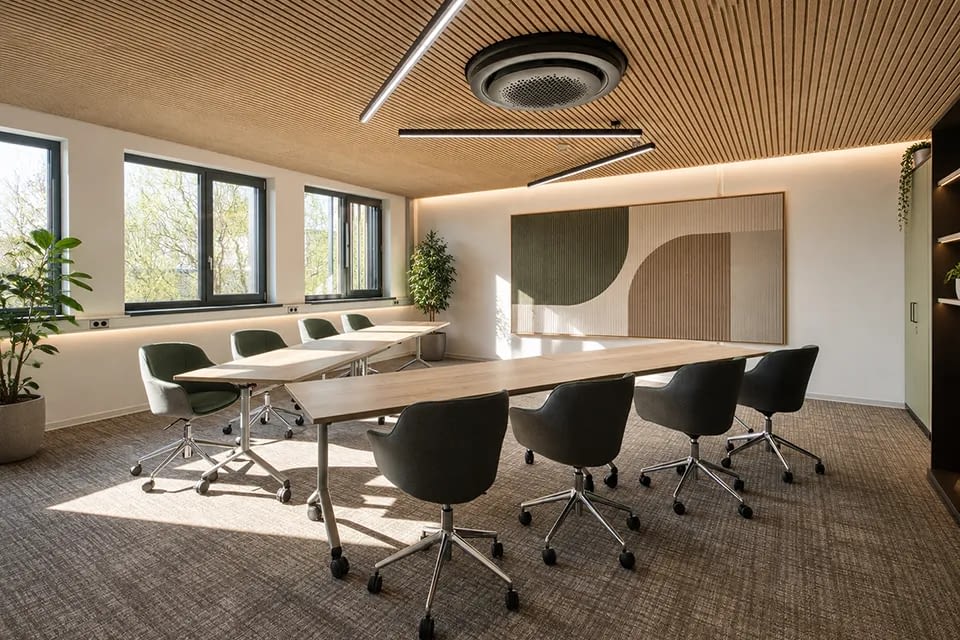 Im Konferenzraum sind grüne Schalenstühle auf Rollen sowie rollbare und klappbare Schreibtische dargestellt.