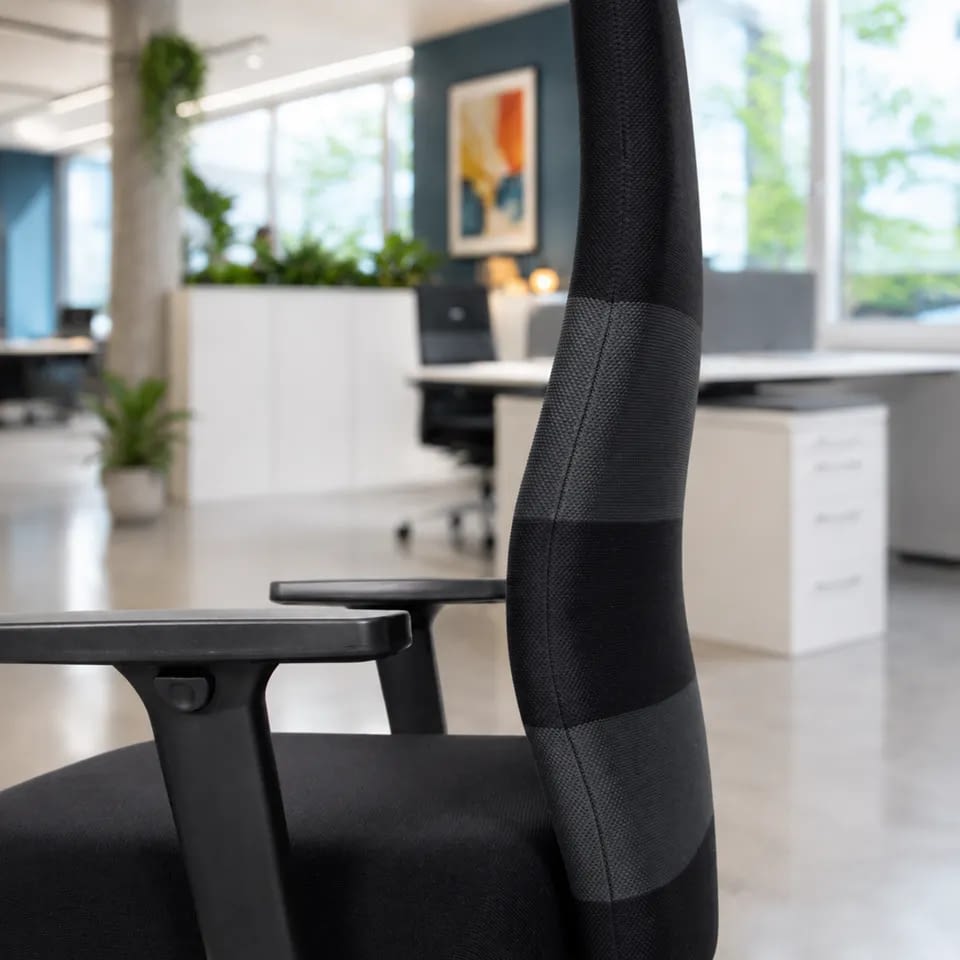 Im Vordergrund steht der ergonomische Bürostuhl agilis comfort in Schwarz-Grau, mit Fokus auf die ergonomische Rückenlehne.