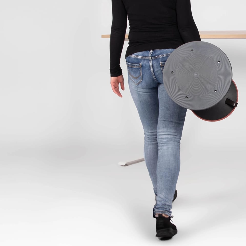 Eine Person trägt den Stehhocker sella flex.