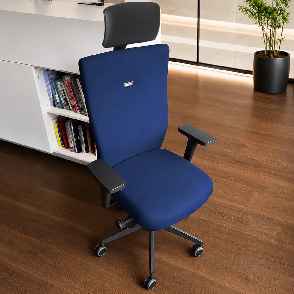 Im Büro steht der ergonomische Bürostuhl agilis eco in dunkelblau mit Kopfstütze aus der Nahperspektive.