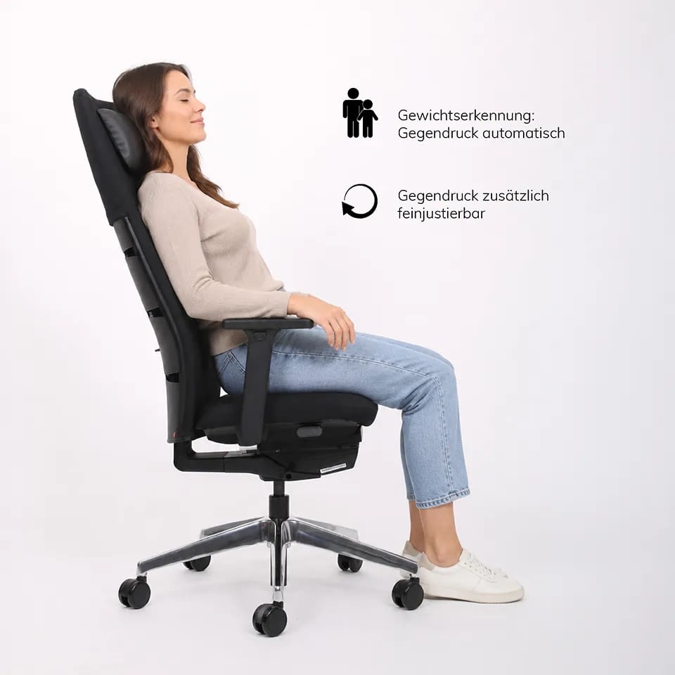 Seitlich lehnt eine Person im schwarzen ergonomischen Chefsessel agilis matrix mit integrierter Kopfstütze zurück.