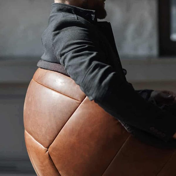 Bild zu Mann, der in einem braunen Retro Loungesessel im Fußball Design sitzt